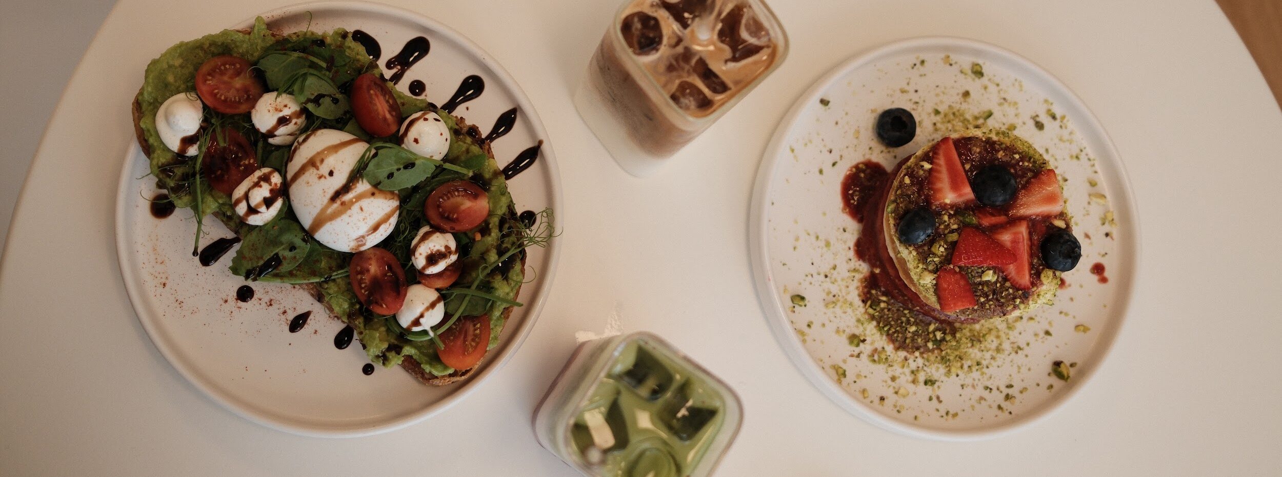 avocado toast pancakes iced coffee and strawberry iced matcha served on white table