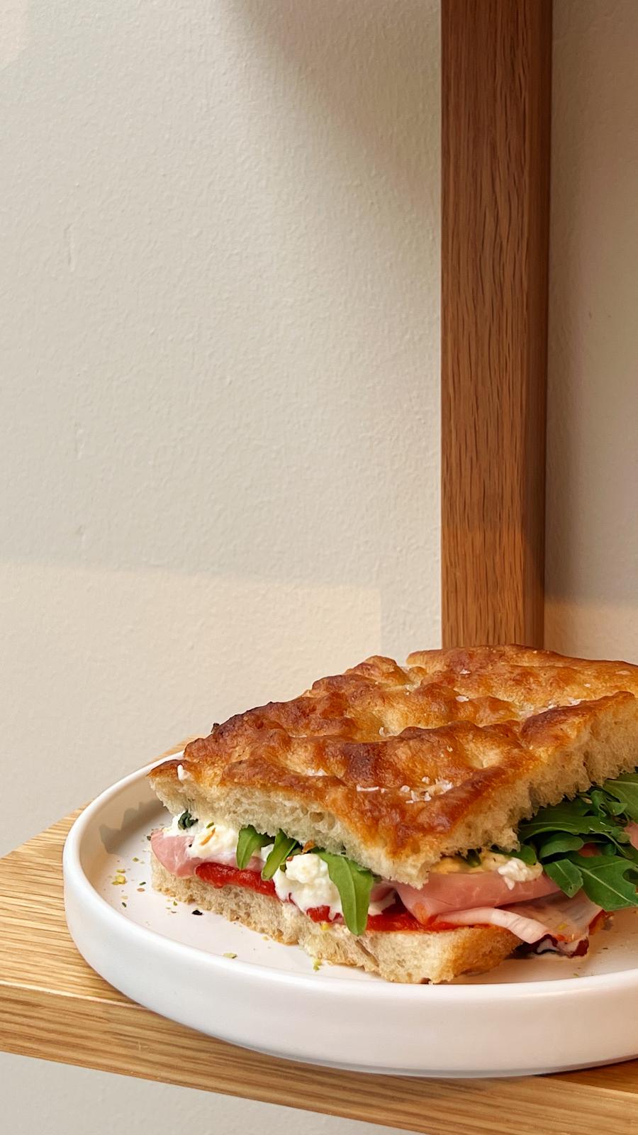 stuffed homemade focaccia on a white plate on a wooden shelf